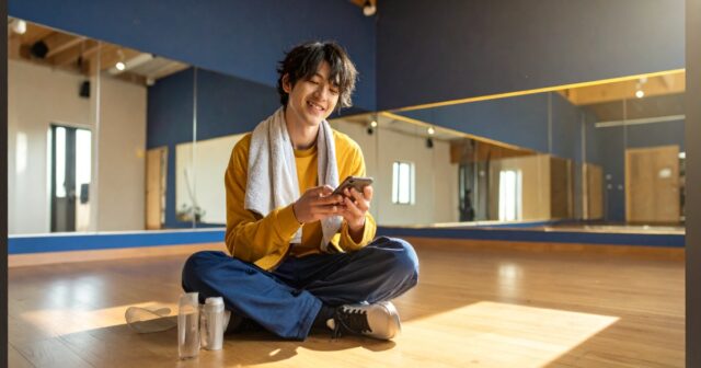 座ってスマートフォンを操作している男性